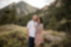 Man and woman pose in front of Boulder, CO foothills during engagement session