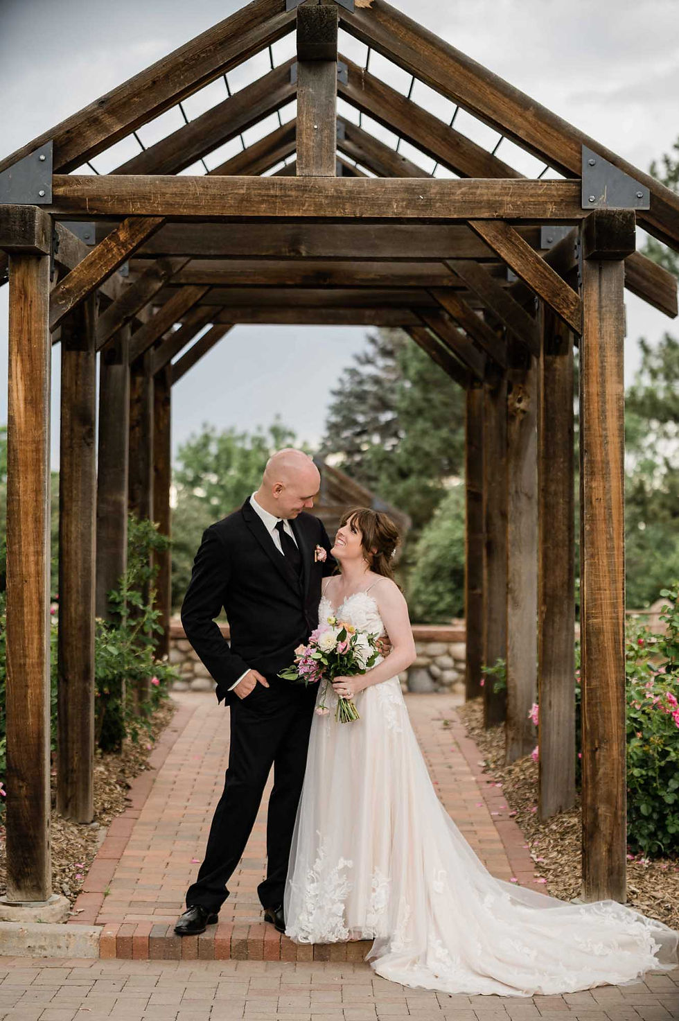 Bride and groom pose under wooden awning at Hudson Gardens