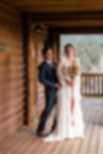 The bride and groom laugh together on the porch at the Ranchstead Inn in Allenspark, CO