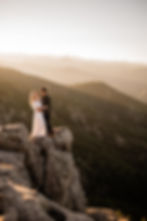 Man and woman look at each other and smile overlooking the foothills during sunset engagement session in Boulder, CO