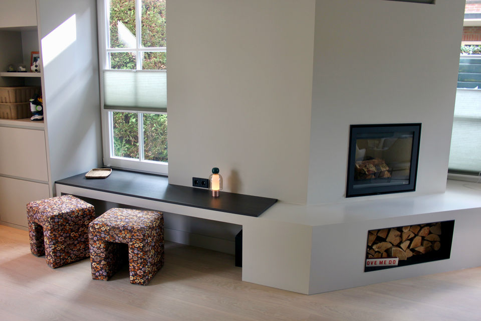 kinderhoek op maat met ingebouwde opbergmogelijkheden, rondom een strakke open haard. Afgewerkt in warme tinten en geplaatst op een eikenhouten vloer,