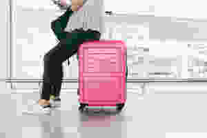 Someone sitting on a suitcase in an airport.