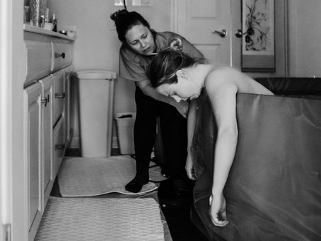 A doula offering support to a woman in labor tub
