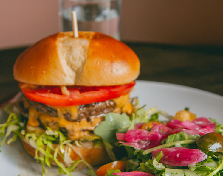 The Gather Burger — double grass-fed beef patty with cheddar, tomato, and shredded lettuce served with a fresh side salad at Gather 22.