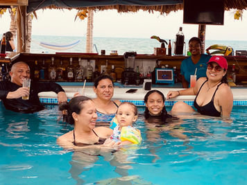 Group of people at Placencia Beachfront Bar enjoying drinks in the pool.