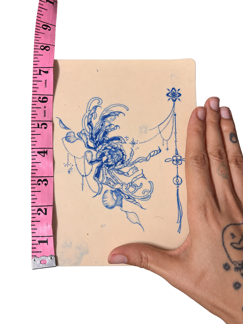 Tattoo practice pad, measuring tape, and hand.png