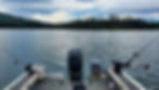 Boat equipped with trolling rods on a serene lake in the Cariboo region, showcasing a typical trolling setup for fishing