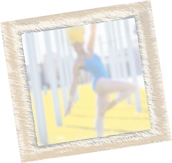 Blurry dancer in blue leotard balancing on one leg outdoors.