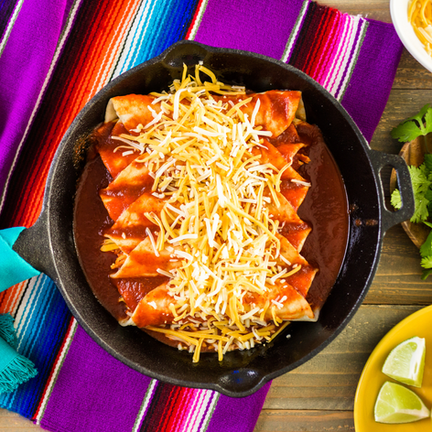 Teller mit überbackenen Enchiladas in roter Sauce, serviert mit Bohnen und Reis.