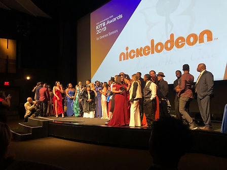 Group of people on stage with the word Nickelodeon on a screen behind them.