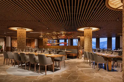 Salle de restaurant aménagée sur mesure avec plafond en lames de bois et colonnes sculpturales