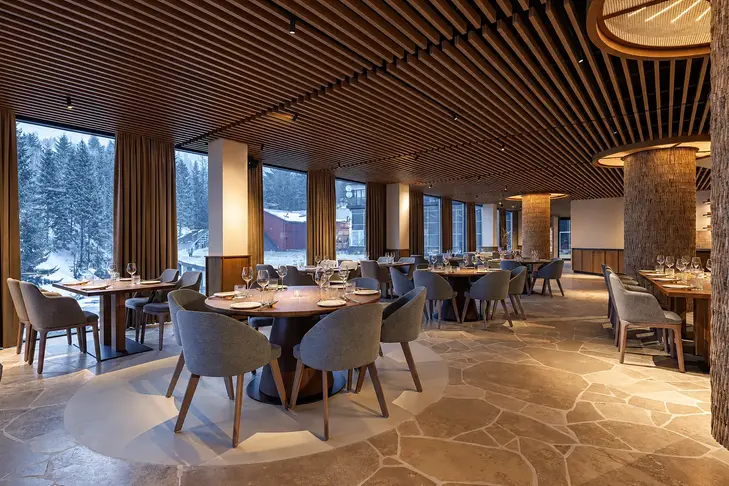 Salle de restaurant panoramique avec plafond en lames de bois et vue sur les montagnes