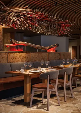 Espace de restaurant aménagé sur mesure avec banquette en bois et installation sculpturale de branches