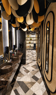 Sanitaires de restaurant aménagés sur mesure avec vasques, miroirs ovales et plafond sculptural