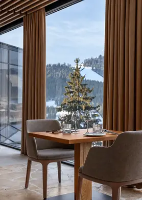 Table en bois dans un restaurant avec baie vitrée donnant sur les montagnes enneigées