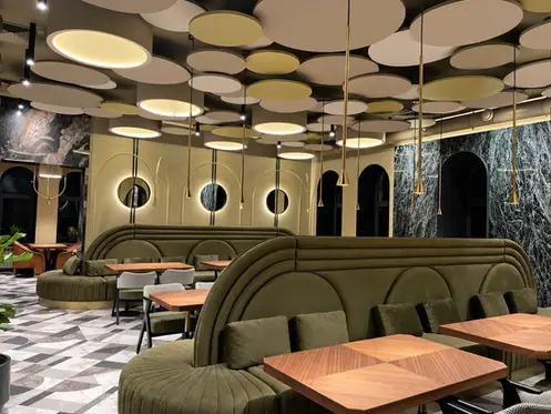 Des banquettes courbes réalisées sur mesure structurent la salle de restaurant, sous un plafond sculptural aux formes organiques.