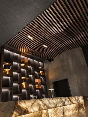 Bar sur mesure en pierre naturelle rétroéclairée, intégré à un intérieur aux lignes architecturales et au plafond structuré en lames de bois.