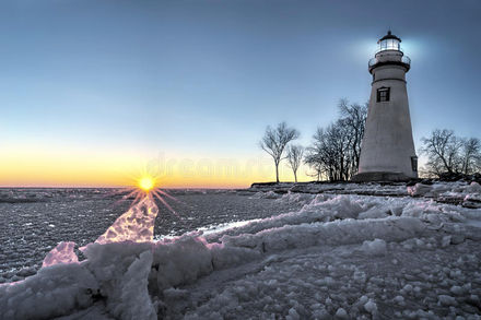 Sunset along a frozen lake with a lighthouse