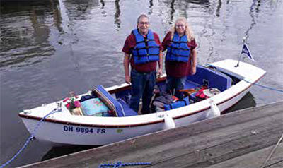 A couple standing in a small electric power boat along a dock