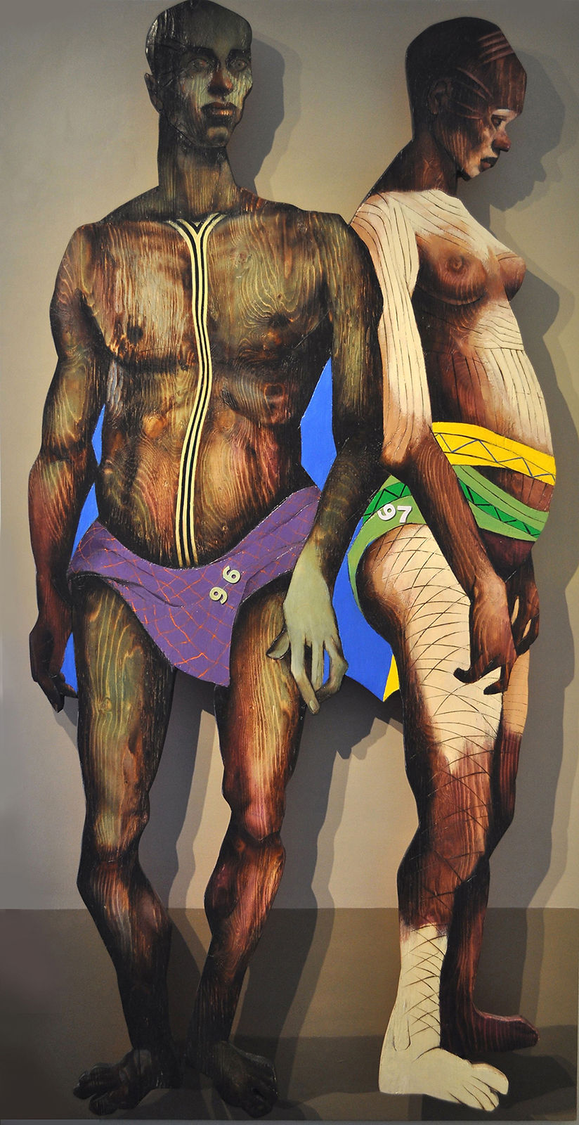 Two figures, one in purple garment with '96', one in green and yellow
