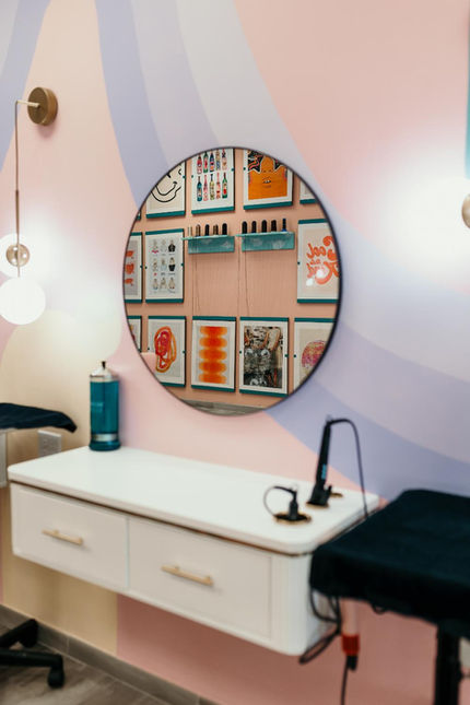 jovi salon Virginia beach, Whimsical nail salon station with floating desk, circular art mirror, pastel wall.