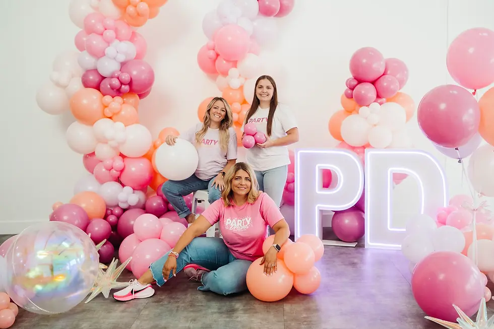 Three women wearing "PARTY DREAMS" shirts pose with pink, peach balloons and "PD" sign.