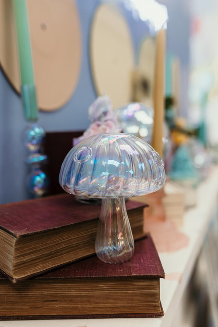 jovi salon Virginia beach,  Iridescent mushroom lamp sits on stacked antique red books, decorative background.