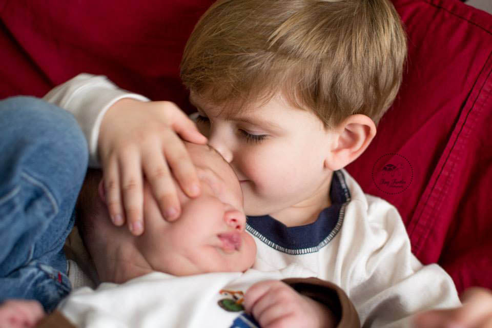Newborn boy snuggling with his big brother. Photo taken by Tiny Turtles Photography in San Diego CA