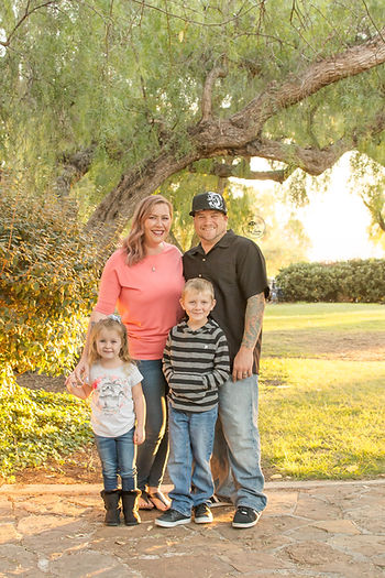 Family of four posing under tree in Presideo Park. Family photo by Tiny Turtles Photography in San Diego CA