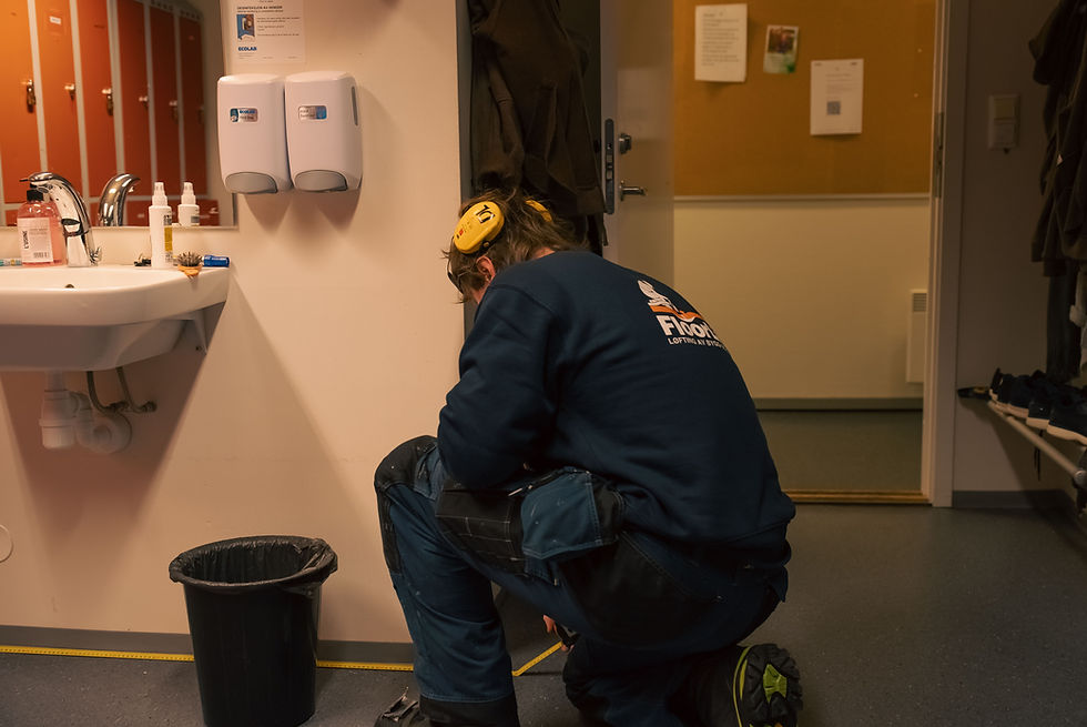 Håndverker med hørselsvern og floorlift-genser kneler på gulv