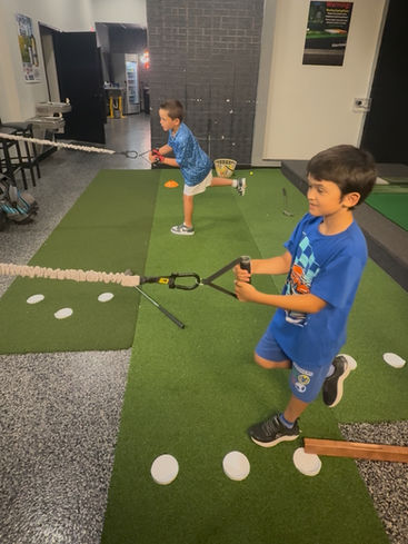 Two boys in blue shirts doing training exercises for golf