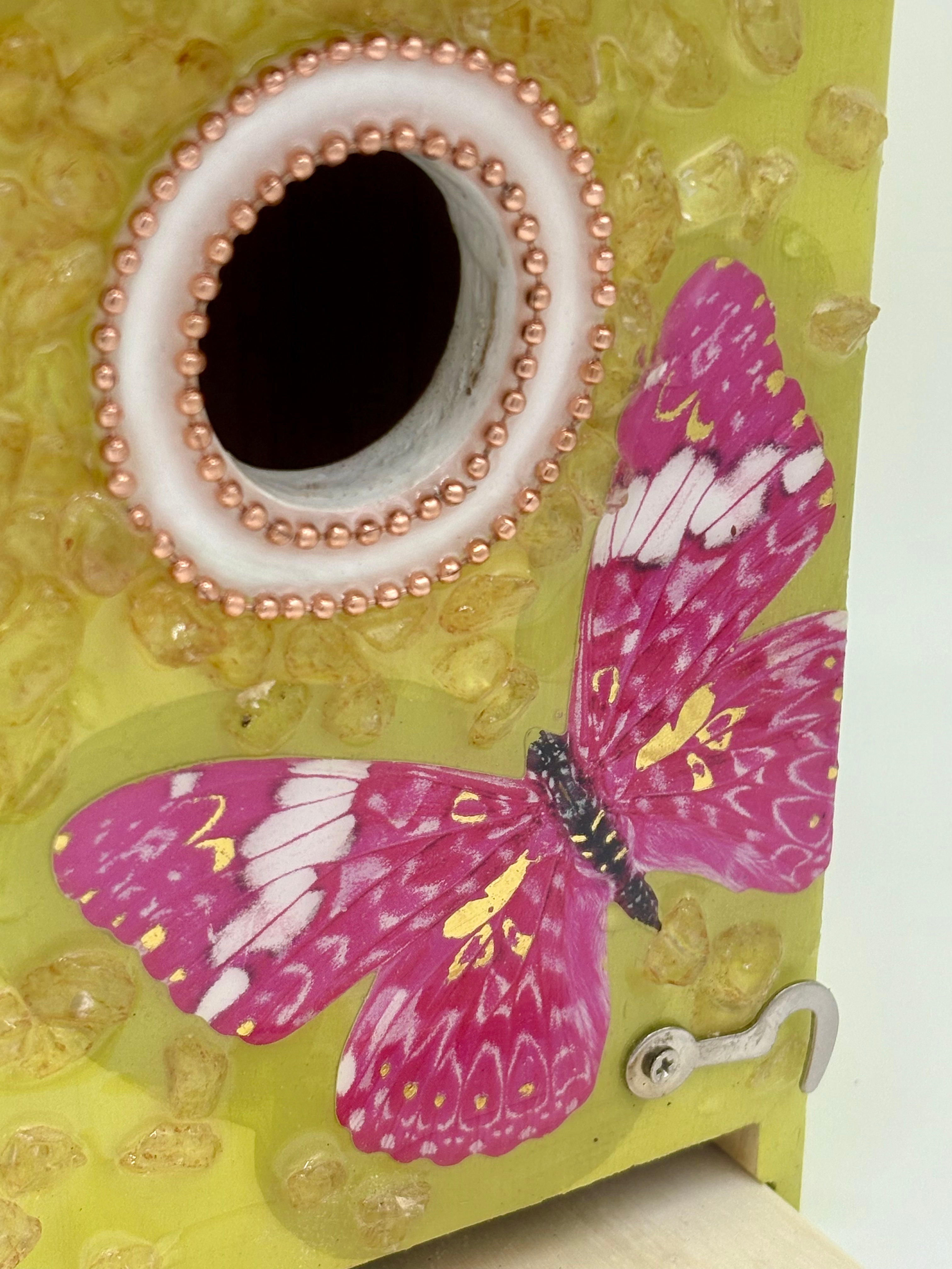 Front angle of yellow birdhouse with clean-out door open and pink butterfly design