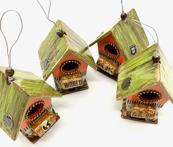 Four mini orange birdhouses with distressed green roof and bottom half of house is a map and a wine cork perch.