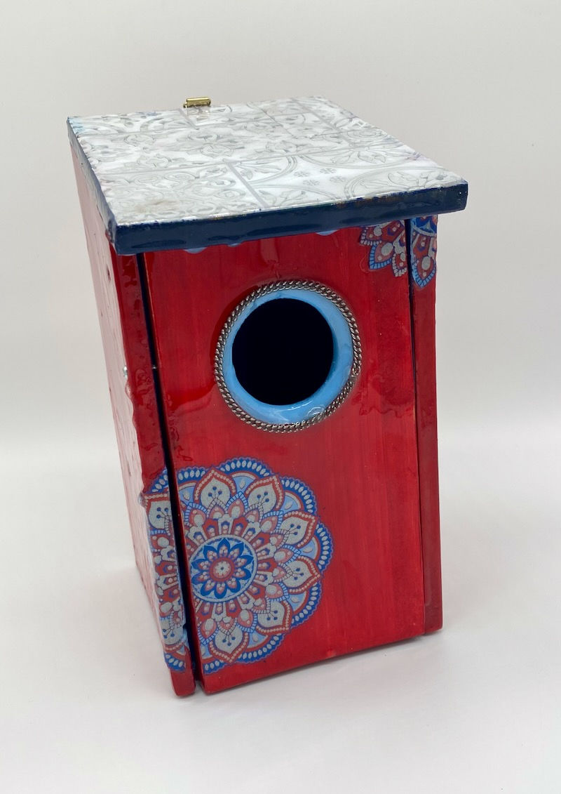 Front view of a red bluebird box with a red, blue and silver mandala and a silver embossed roof.