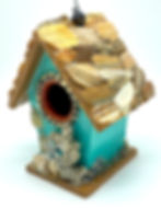 Side view of mini teal birdhouse featuring the beach and with shells covering the roof.