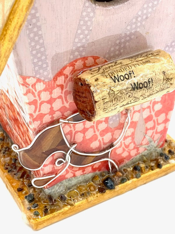 Thumbnail: Close up of a handmade wire dog and a wine cork perch on a birdhouse.