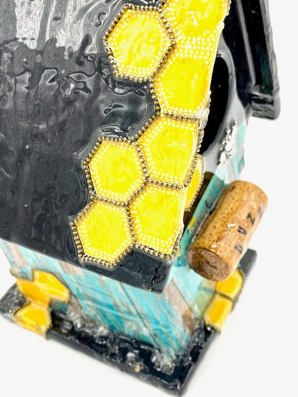 Thumbnail: Side view of a bee themed birdhouse with a black, yellow and teal color pallet and a cork perch.