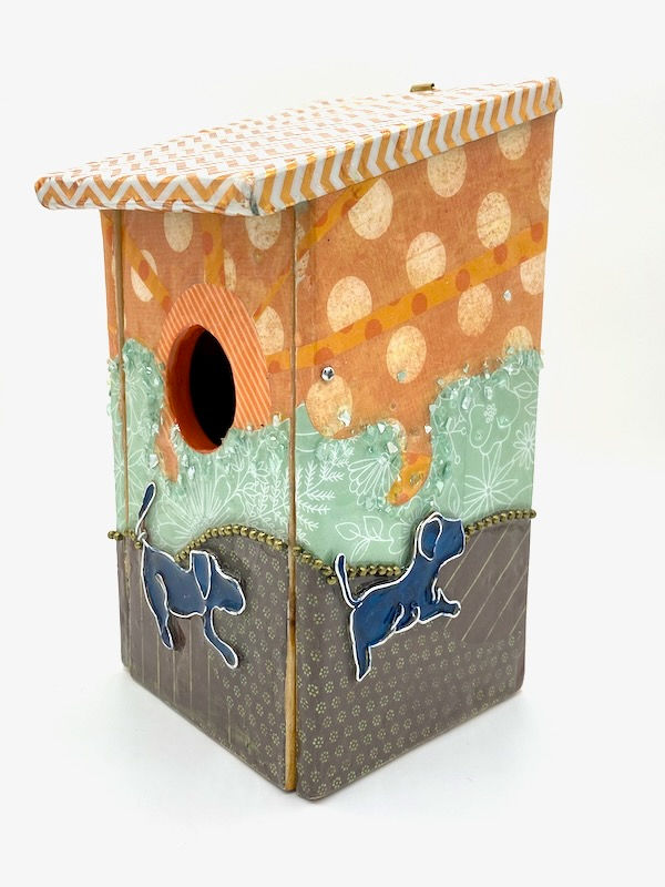Thumbnail: Side view of a bluebird box with handmade wire dogs on a whimsical orange and teal landscape.