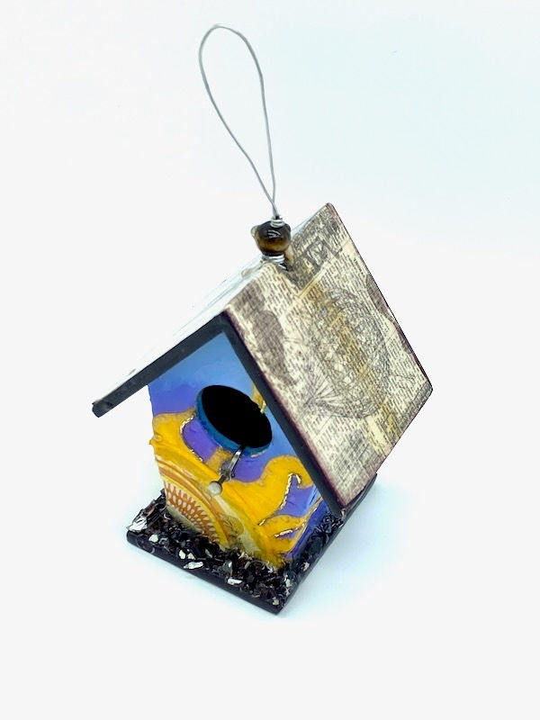 Side view of mini blue birdhouse with a sun outlined in metal beads.