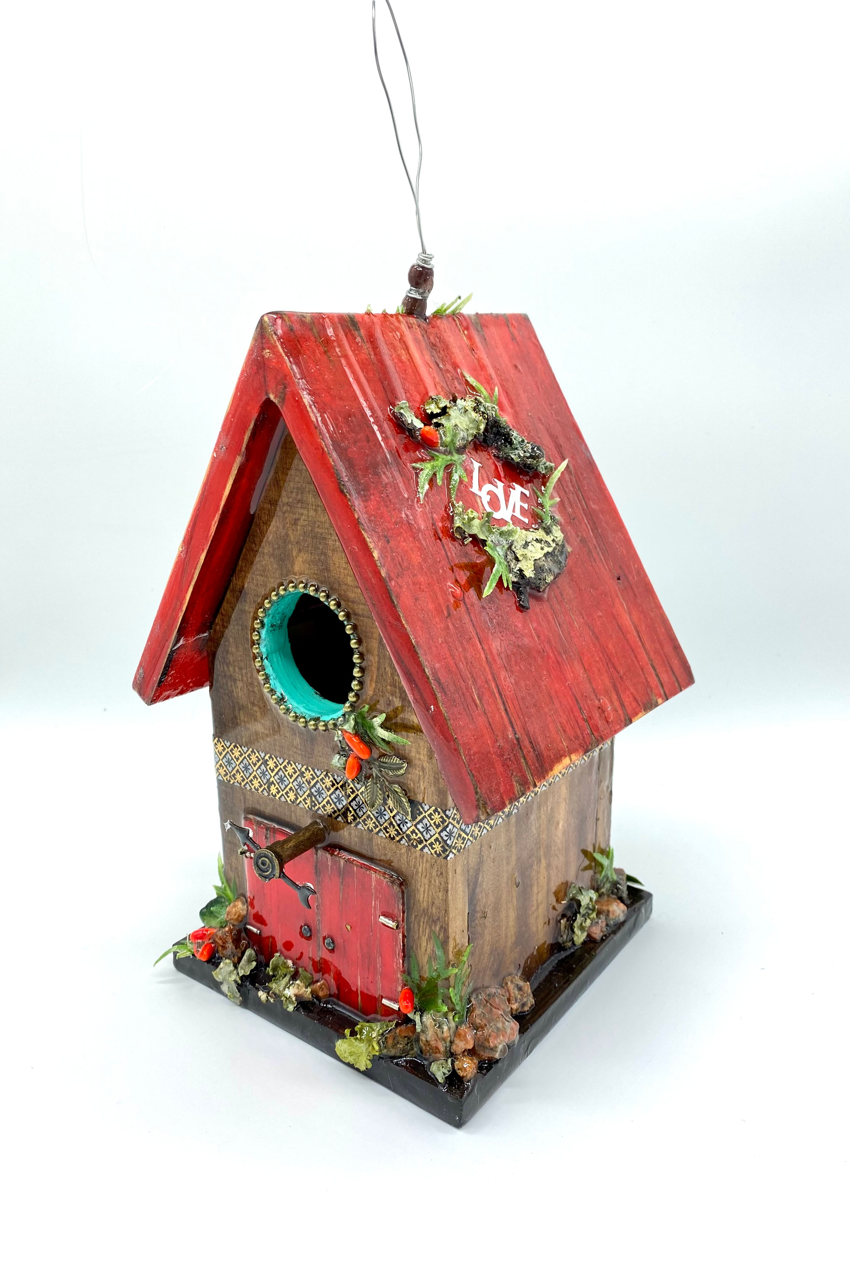 Side view of rustic farmhouse birdhouse, with a weathered red roof and barn door.
