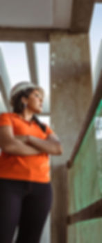 Kellyany com polo laranja e capacete em obra