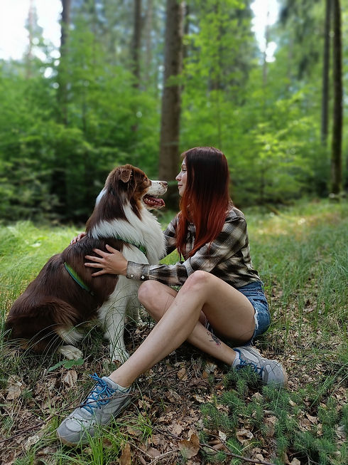 Bara and her australian shepherd cuddle in the forest.