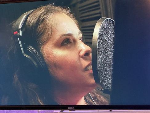 Actor wearing headphones performs at a studio microphone during voiceover training at Babcock Studios.