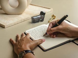 Een hand die een vulpen vasthoudt en schrijft in een notitieboek