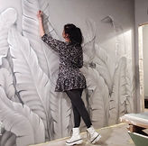 Mira Sovia dipinge foglie di banano grigie sulla parete di un appartamento: un disegno murale leggero ed elegante.
