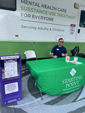 Starting Point staff member sitting at a table in front of the Mobile Health Clinic