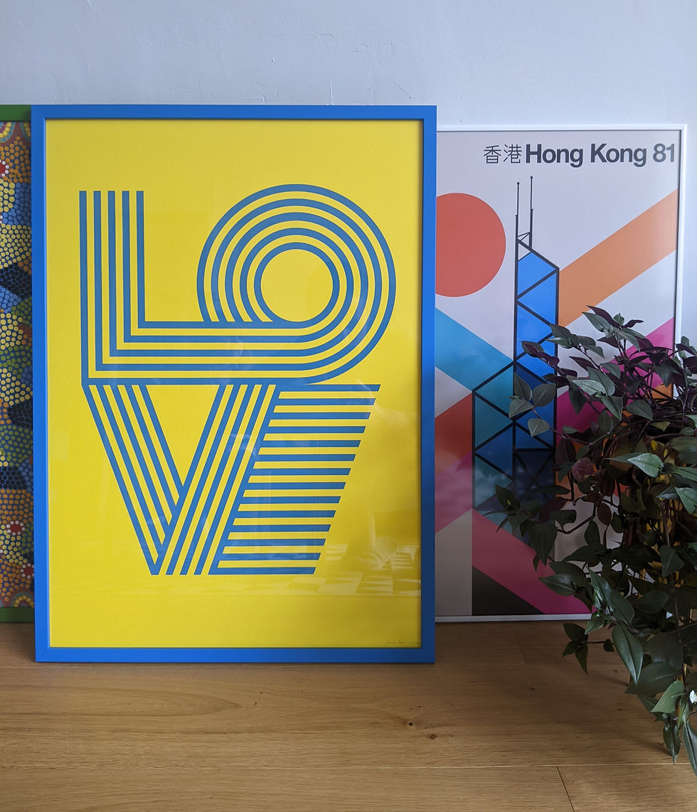 Framed screen print that spells 'LOVE' resting against a wall.