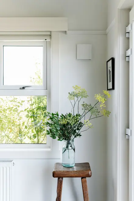 A beautiful window of an old red brick house with a base of flowers