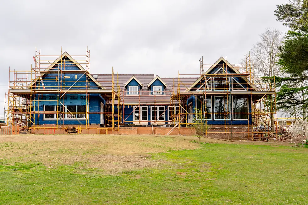 Building a custom home in progress with scaffolding and framing structure