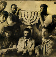 The excavator Nahum Slouschz (front row, center) and the workers, members of Degania and Kinneret, with the seven-branched stone menorah discovered at the ancient synagogue at Hammat Tiberias in 1921, the first excavation carried out by the Society